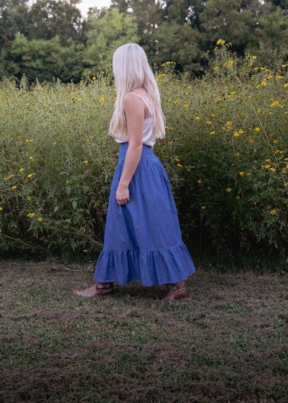 Side view of the blue chambray Demelza midi skirt with brown boots