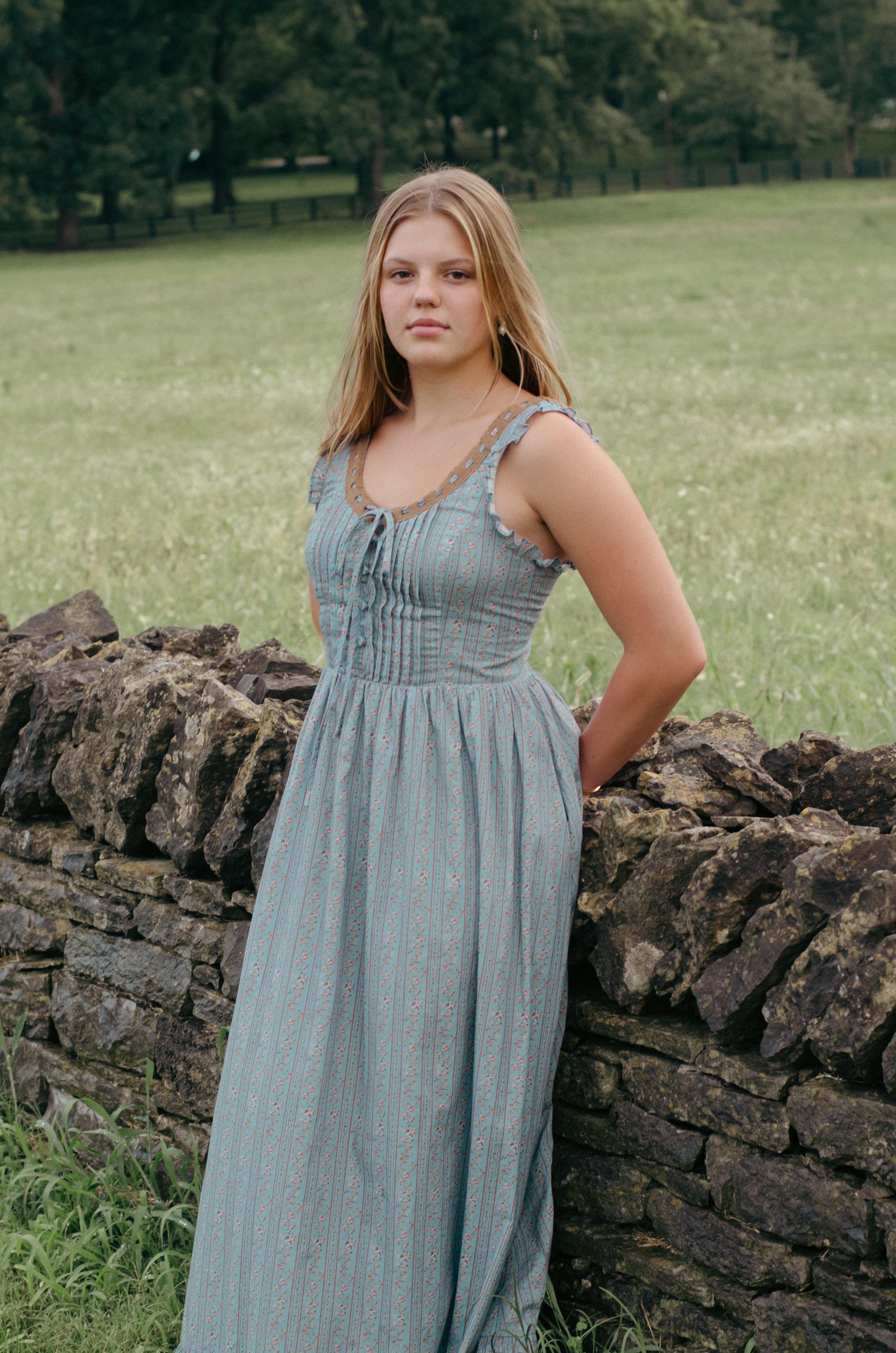 Woman wearing the Avaire Collective Adaline dress, a dusty blue floral cotton corset-style dress with eyelet lace neckline
