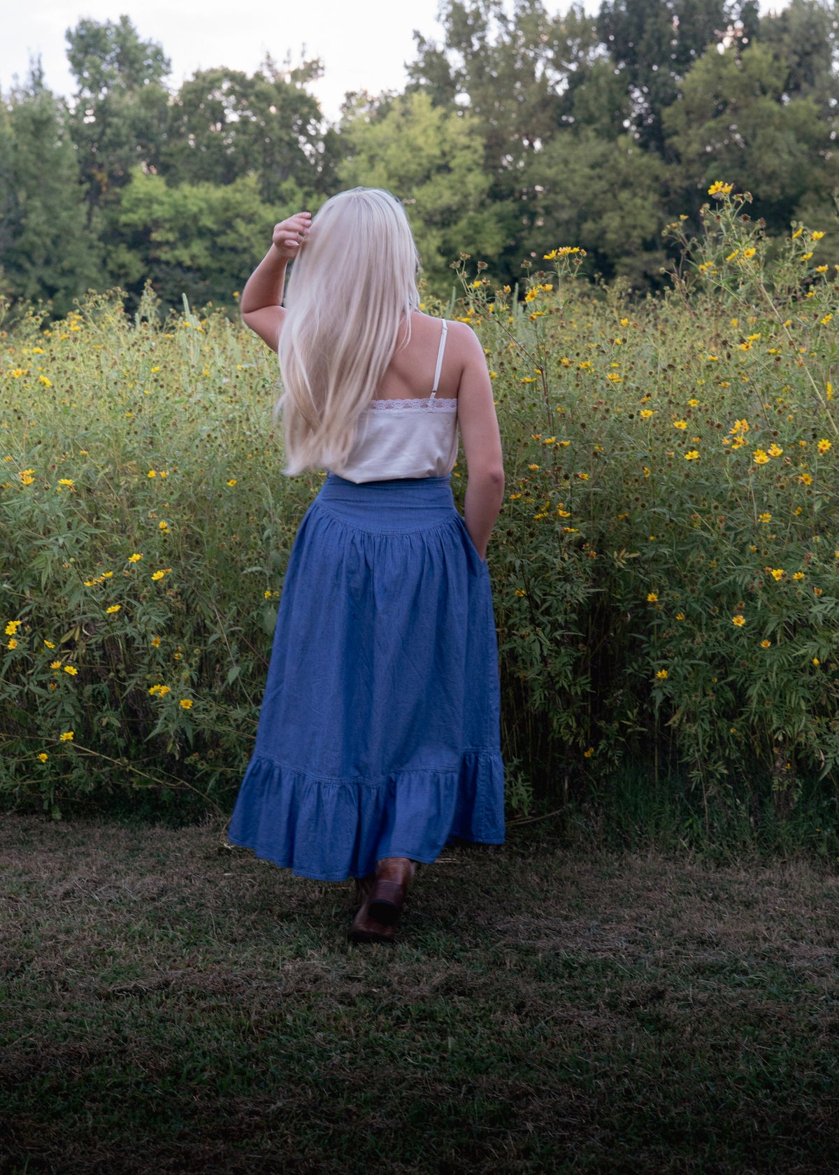 Back view of the Demelza Skirt in blue pinstripe chambray showing the fitted waistband, gathered skirt, and ruffled hem